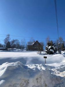 a yard covered in snow with a house in the background at Apartament Guziczek in Nowy Targ