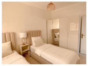 1 Schlafzimmer mit 2 Einzelbetten und einer Lampe in der Unterkunft Appartement de luxe Al hoceima in Al Hoceïma