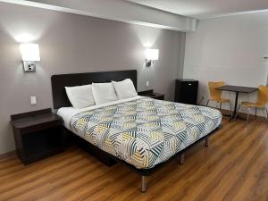 Motel 6-Greensboro, NC - Airport في جرينسبورو: غرفة نوم بسرير وطاولة وكراسي