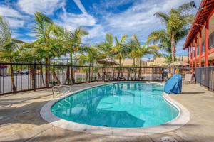 a swimming pool with a fence and palm trees at Motel 6 Carlsbad, Ca- North in Carlsbad