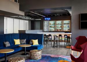 a bar with a blue couch and tables and chairs at Aloft Leawood-Overland Park in Overland Park
