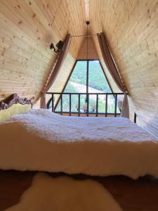 a bed in a room with a large window at Cozy cabin in Tbilisi City