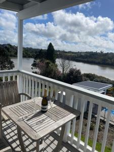a picnic table on a porch with a view of a river at Pickmere Waters in Kerikeri