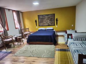1 dormitorio con 2 camas y pared amarilla en Solar dos Reis Apartamento Topázio en Ouro Preto