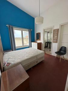 ein Schlafzimmer mit einem Bett, einem Fenster und einem Stuhl in der Unterkunft Apartamento sobre Gorlero in Punta del Este