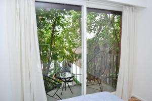 Schlafzimmer mit Glasschiebetür zum Balkon in der Unterkunft Chacabuco 255 by depptö in San Isidro