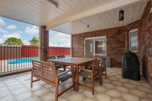 patio z drewnianym stołem i krzesłami oraz basenem w obiekcie Hillvue Lodge w mieście Tamworth