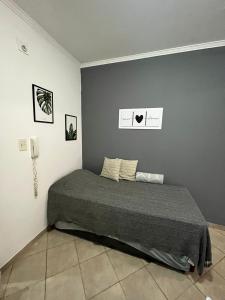 1 cama en un dormitorio con una pared gris en Dpto Temporario centro con garage en Corrientes