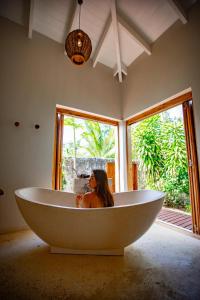 Pangona的住宿－Nakatumble - Luxury Sustainable Villa with Farm，坐在一个房间里浴缸里的女人