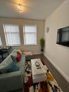 a living room with a couch and a flat screen tv at Lovely 2 Bedroom Apartments In Manchester Close To City Centre And Manchester City Stadium #1 in Manchester