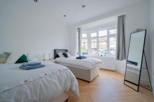a bedroom with two beds and a mirror and a window at Modern 5 bed home in Ealing, free driveway parking, sleeps 8 in Harrow on the Hill