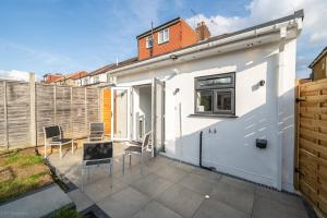 a white house with a patio and a fence at Modern 5 bed home in Ealing, free driveway parking, sleeps 8 in Harrow on the Hill
