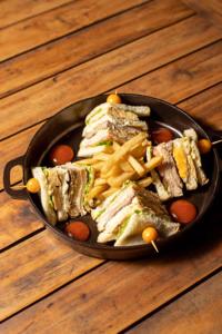 a pan filled with sandwiches and french fries on a wooden table at Hotel Wayra Club in Acacías