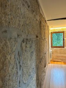 a stone wall in a room with a window at Villa Margaridi in Guimarães