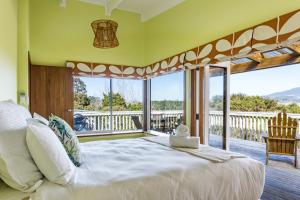 a bedroom with a large bed and a balcony at Karioi View in Raglan