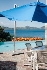 un parasol bleu assis à côté d'une table et de chaises dans l'établissement Beautiful 3 story 8,000 sq ft Oceanside Mansion, à Nevis