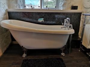 a white bath tub in a bathroom with a window at Cozy Cottage - Near Brew Pub / Snowdonia National Park. in Caernarfon