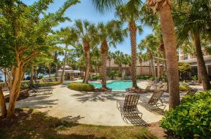 a resort with a pool with palm trees and chairs at Reflections by Panhandle Getaways in Panama City Beach