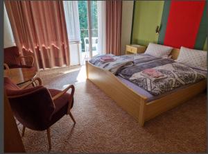 a bedroom with a bed and a chair and a window at Fitnesshotel Bergquell in Altenau