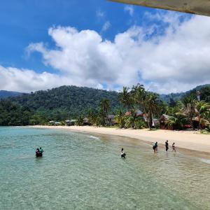 Un groupe de personnes debout dans l'eau sur une plage dans l'établissement Permai Chalet Tioman, à Kampong Juara