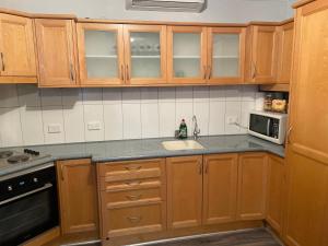 a kitchen with wooden cabinets and a sink at Quaint Flat, Outside Dog Friendly, near hospital in Geraldton