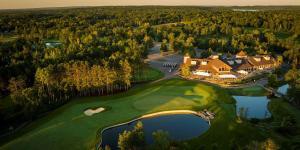 an aerial view of a large house with a golf course at AmericInn by Wyndham Baxter Brainerd in Baxter
