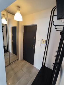 a hallway with a black door and a mirror at Studio 2 Apartment in Ełk