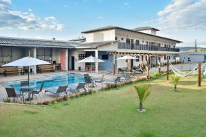 uma piscina com cadeiras e guarda-sóis ao lado de um edifício em Flats Charme do Cerrado em Pirenópolis