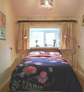a bedroom with a bed with a floral blanket at Cozy Cottage - Near Brew Pub / Snowdonia National Park. in Caernarfon