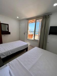 sypialnia z dwoma łóżkami i oknem z widokiem w obiekcie Serafy City Center Hostel and Pool for Foreigners Adults Only w mieście Hurghada
