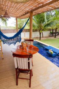 een houten tafel en stoelen naast een zwembad bij Ville Santorinni in Japaratinga +12 foto's