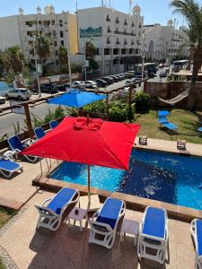 a red umbrella and chairs next to a swimming pool at Serafy City Center Hostel and Pool for Foreigners Adults Only in Hurghada