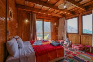 een slaapkamer met een bed in een kamer met ramen bij Dar Aymane in Imlil