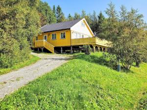 a yellow house on a hill next to a dirt road at 6 person holiday home in Naustbukta-By Traum in Naustbukta