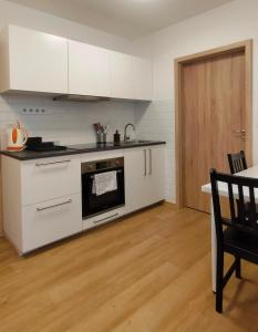 een keuken met witte apparatuur en een houten vloer bij Apartment Staňkova in Brno