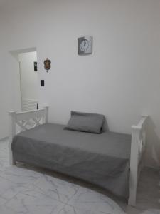 a white bedroom with a bed and a clock on the wall at Departamento Ideal para disfrutar Mendoza in Mendoza