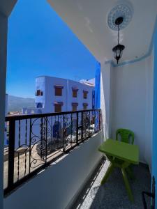 balcón con mesa verde y vistas en Casa chaara, en Chefchaouen