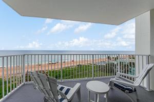 a balcony with chairs and a table and a view of the beach at Updated Oceanfront Condo! Come Relax by the Sea! in Ormond Beach