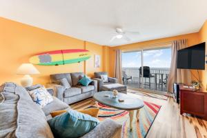 a living room with a couch and a surfboard on the wall at Updated Oceanfront Condo! Come Relax by the Sea! in Ormond Beach