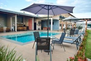 a patio with chairs and an umbrella next to a pool at Flats Charme do Cerrado in Pirenópolis