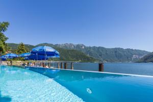 una piscina con sombrillas azules y un cuerpo de agua en Hotel Riviera en Melide