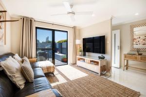 een woonkamer met een bank en een tv bij Alkira - Pet Friendly - 4 Mins Walk to Beach in Culburra Beach