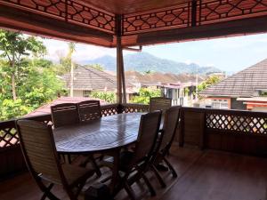 una mesa y sillas en un porche cubierto con vistas en Palanta Roemah Kajoe Syariah Villa, en Kampungdurian