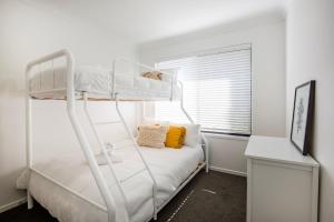 a white bedroom with a bunk bed and a window at Alkira - Pet Friendly - 4 Mins Walk to Beach in Culburra Beach