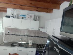 cocina pequeña con armarios blancos y TV en En lo de su en Calchaquí