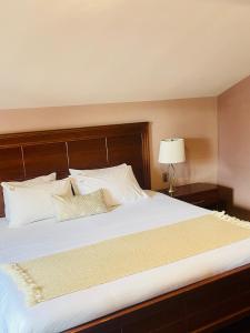 - une chambre dotée d'un grand lit avec des draps et des oreillers blancs dans l'établissement La Estancia, à San Cristóbal de Las Casas