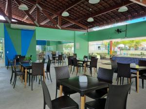 ein Restaurant mit Tischen und Stühlen und grünen Wänden in der Unterkunft Palm Village Acqua Porto de Galinhas por Brevelar in Porto De Galinhas