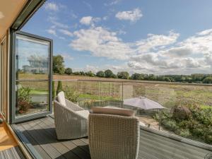 einen Balkon mit Stühlen und Blick auf ein Feld in der Unterkunft The Dutch Barn in Leominster