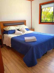 Una cama azul con dos toallas encima. en Linda y cómoda cabaña en un entorno natural, en Los Ángeles