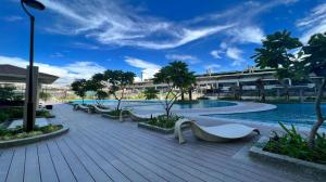 a resort with a pool with benches and trees at 1BR Prisma Residences DMCI Stylish Condo in Manila